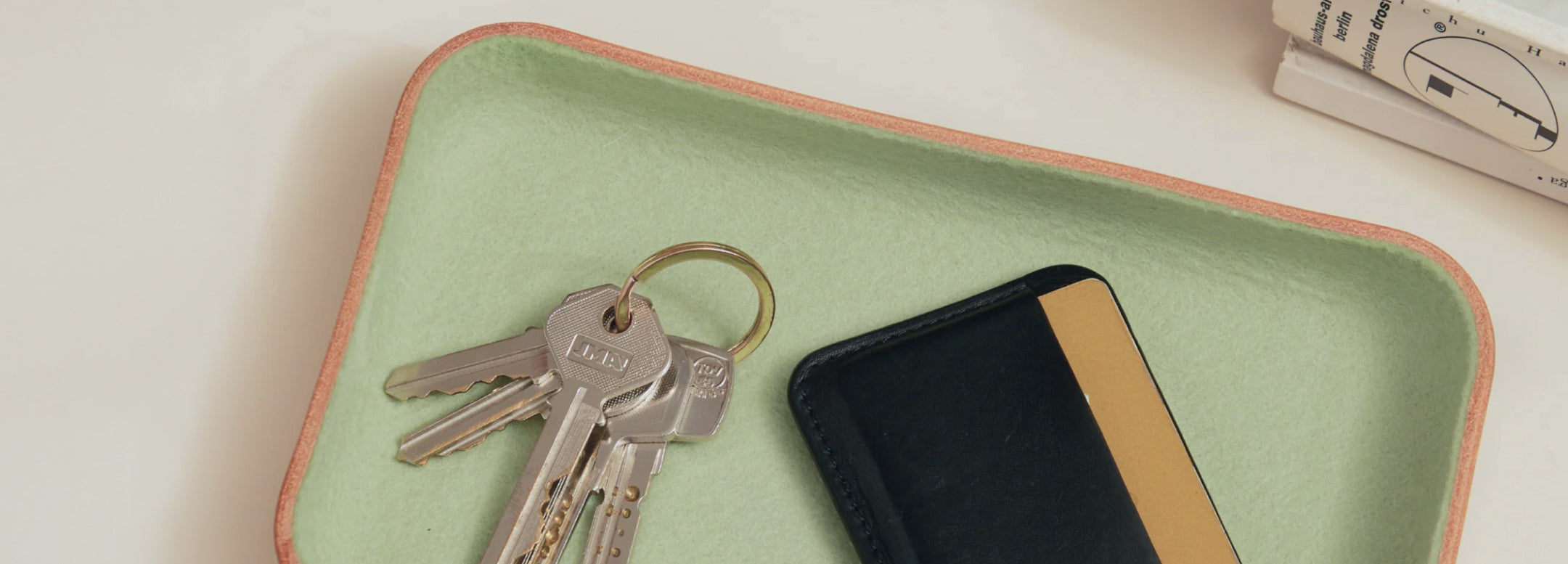 Two trays on a light surface hold office supplies: pens, pencils, clips, eraser, scissors, eyeglasses, a notebook, AirPods case, clear push pins, and a pack of chewing gum.