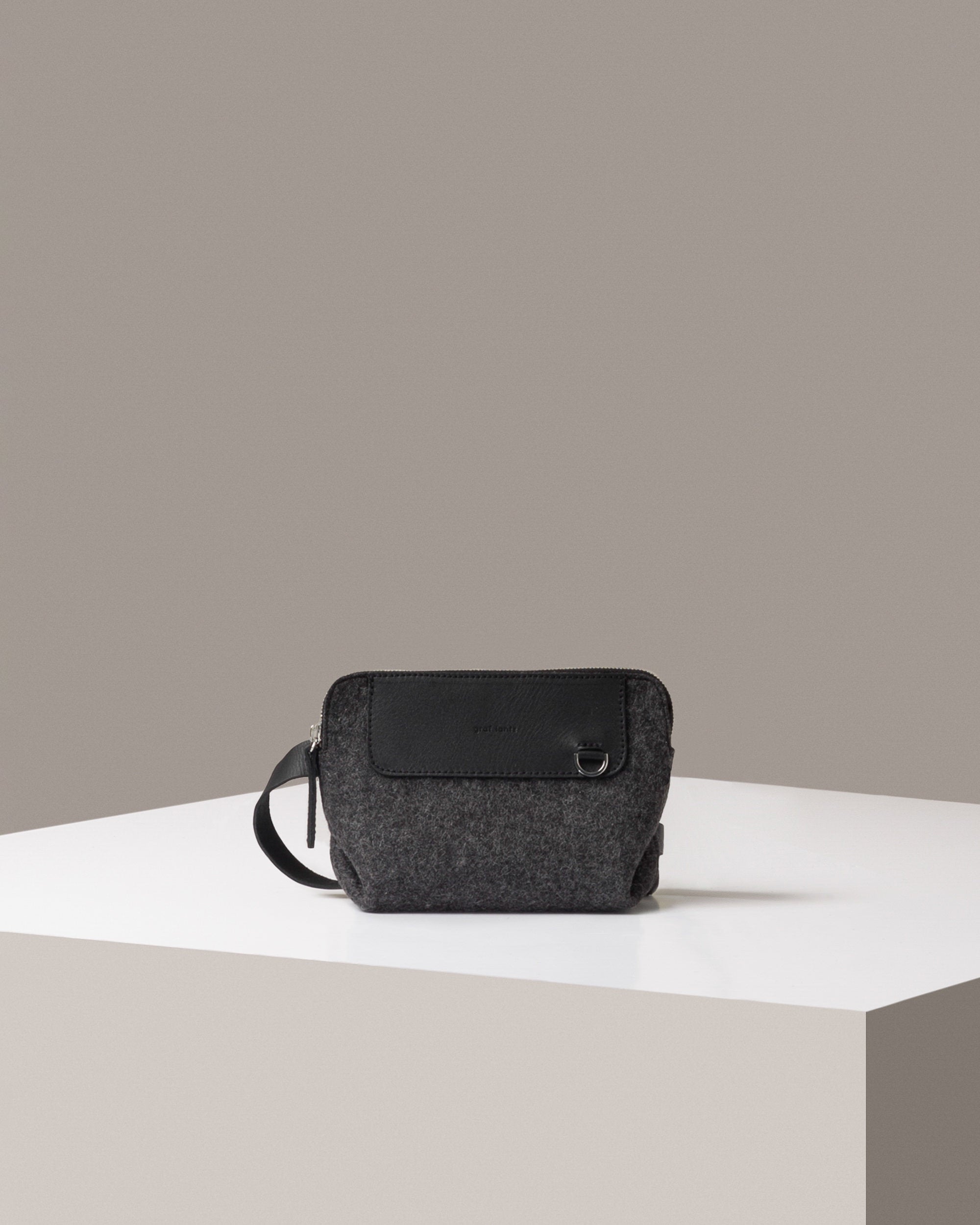 A Bedford Merino Wool Felt Belt Bag by Graf Lantz in dark gray standing on a white base, front view