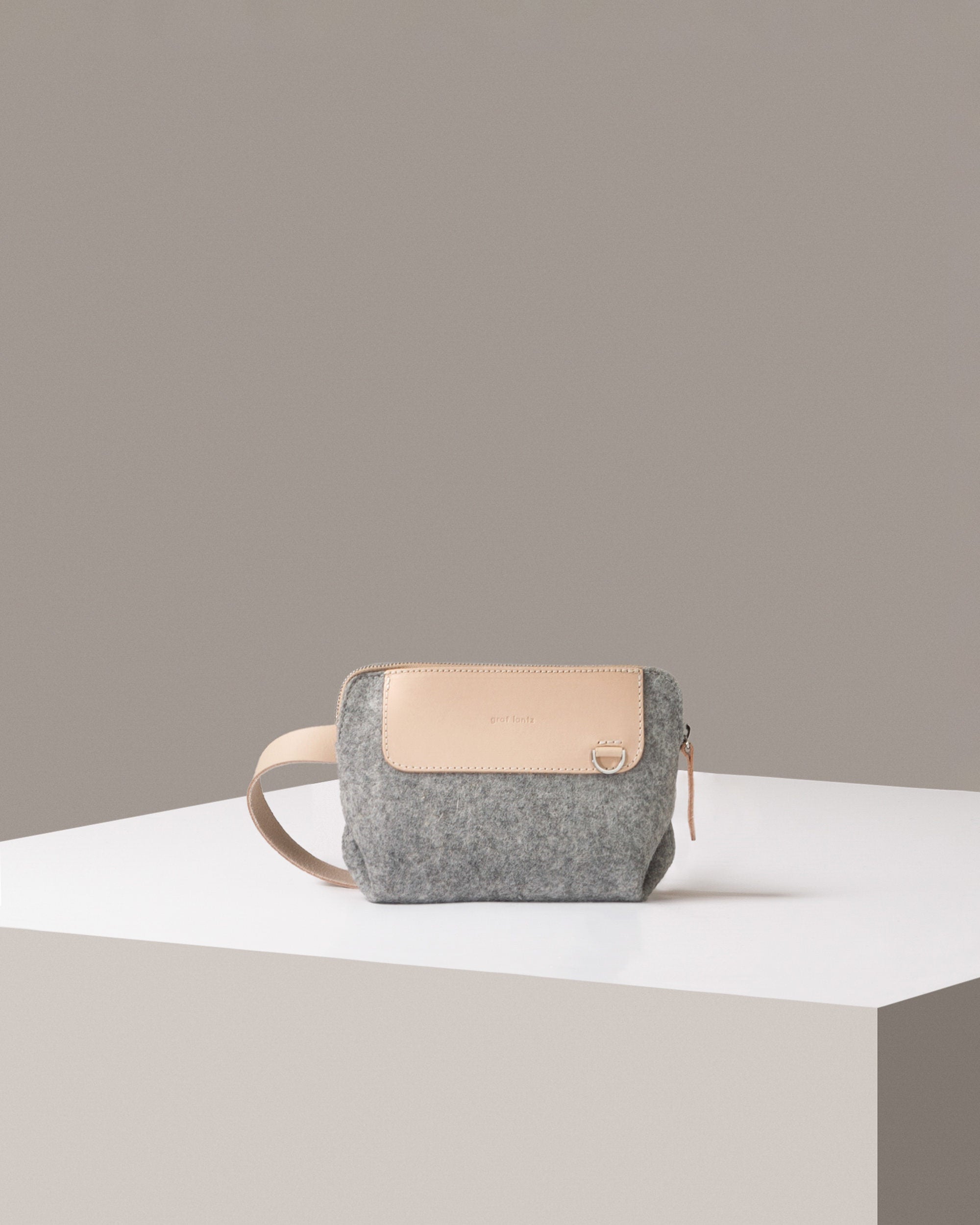 A Bedford Merino Wool Belt Bag in light grey standing on a white base, front view