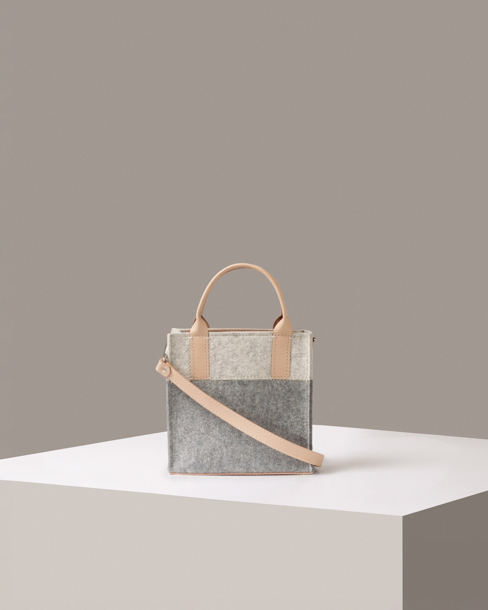 A small-sized Merino Wool Felt Tote bag standing on a white base, front view