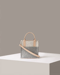 A small-sized Merino Wool Felt Tote bag standing on a white base, front view