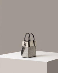 A timeless crossbody bag in gray and white on a white base displayed in a side-view