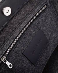 Interior view of Frankie Merino Wool Tote featuring a zippered felt pocket, black leather trim, and nickel hardware, highlighted in detail