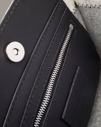 Interior view of a gray Jaunt Mini Merino Wool Felt Tote featuring a zippered leather pocket, a magnetic top closure, and nickel hardware, highlighted in detail