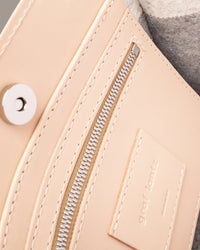 Interior view of a gray Jaunt Mini Merino Wool Felt crossbody bag featuring a zippered-leather pocket, beige leather trim, and a magnetic snap closure, highlighted in detail