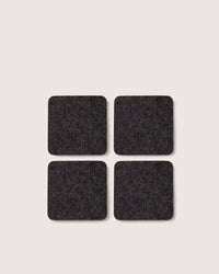 Four premium German Merino wool coasters by graf lantz, in a two-by-two grid, made from black felt on a light background.