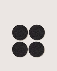 Four round, black felt pads by graf lantz, crafted from premium German Merino wool, are placed in a square pattern on a plain white background.