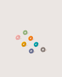 Eight plush rings crafted from Merino wool by graf lantz are arranged diagonally on a white background. In vibrant shades of pink, green, orange, blue, teal, yellow, purple, and gray, they serve as chic host gifts or wine markers.