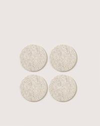 Four textured beige felt pads, crafted from Merino wool by graf lantz, are arranged in a square pattern on a plain white background. Ideal as stylish coasters or durable beer mats for any setting.