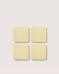 Four beige Graf Lantz sticky notes, like elegant home décor coasters, are arranged in a 2x2 grid on a light gray background. Faint text appears on the bottom right note. Shadows create a subtle 3D effect, adding depth and charm to your space.