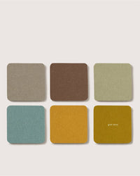 Six square Graf Lantz Merino wool coasters in muted colors (gray, brown, green, blue, yellow, mustard), arranged two by three on a light background. The bottom right coaster features the brand name—ideal beer felt accents.