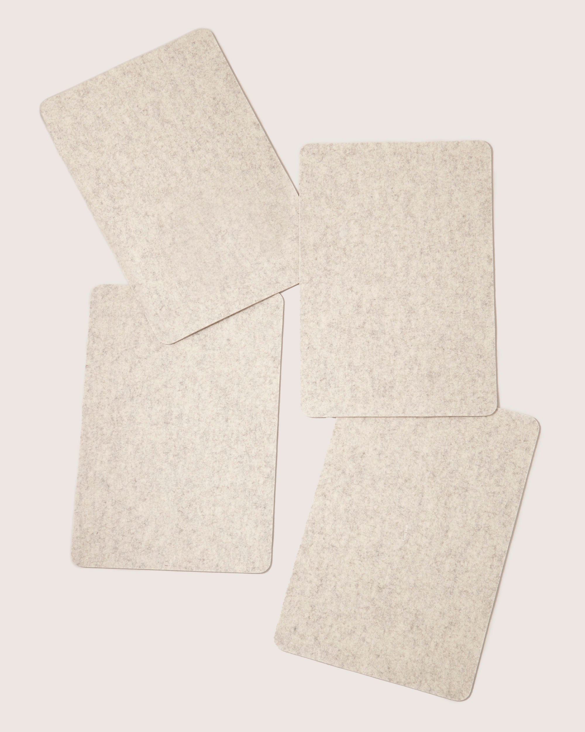 Four blank rectangular graf lantz cards with a designer-inspired textured surface are arranged in a scattered pattern on a plain background, each slightly overlapping the others for an elegant display.