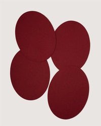 Four overlapping, round, dark red felt coasters by Graf Lantz are arranged on a plain white background.