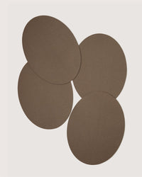 Four overlapping brown ovals on a light background, evoking sustainable tableware like Graf Lantz Merino wool placemats from their designer packs.