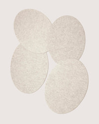 Graf lantz offers sustainable Merino wool felt pads in a light gray, oval design. Arranged artfully on a white background, these designer-inspired pads have overlapping edges that create a unified pattern with a soft texture.