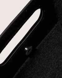 A graf lantz dark gray Merino Wool rectangular tote bag features a cutout handle and small circular perforations on the lower half. Set against a light neutral background, it highlights the minimalist design.