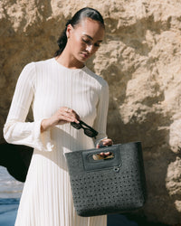 A graf lantz dark gray Merino Wool rectangular tote bag features a cutout handle and small circular perforations on the lower half. Set against a light neutral background, it highlights the minimalist design.