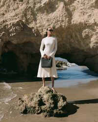 A graf lantz dark gray Merino Wool rectangular tote bag features a cutout handle and small circular perforations on the lower half. Set against a light neutral background, it highlights the minimalist design.