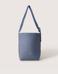 The Graf Lantz minimalist blue shoulder bag is designed for everyday use, featuring a wide strap and small white logo near the bottom. Its sleek, modern style stands out on a light background.