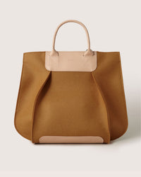 Introducing the Graf Lantz Frankie Tote, a tan leather handbag with beige handles and accents that enhance its soft edges. Its spacious interior and elegant, simple design make it the versatile accessory for any occasion.