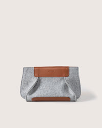 Introducing the graf lantz Frankie Merino Wool Clutch: a stylish, sustainable accessory made from light gray felt with brown leather accents. This rectangular piece features an embossed logo on the top leather patch and sits beautifully against an off-white background. Perfectly chic for fashion enthusiasts.