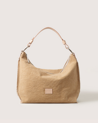 A tan suede Graf Lantz Hana Hobo bag featuring a single light Vachetta leather shoulder strap, silver hardware, and a small square front patch, shown against a plain light background.