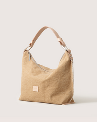 A tan Graf Lantz Hana Hobo bag with a wide Vachetta leather shoulder strap, silver zipper closure, and a small square front patch, displayed against a plain light background.