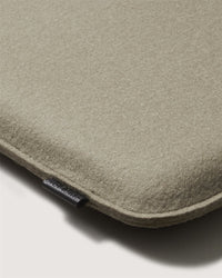 Close-up of a beige, soft-textured Graf Lantz fabric case with rounded edges, ideal for a meditation cushion. A small black fabric tag appears along the left seam. The background is a plain, light surface.