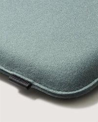 A close-up of a soft, light teal felt laptop sleeve by Graf Lantz with rounded edges and a small black fabric tag on the seam, echoing the calming hues often seen in meditation cushion designs.