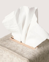 A close-up of a graf lantz tissue box featuring white tissues emerging from a soft, textured beige cover crafted from sustainable materials with leather trim. Ideal for eco-conscious design lovers.