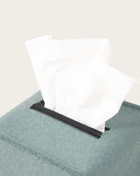 A close-up of a Graf Lantz premium Merino wool tissue box cover in soft teal, featuring a white tissue emerging from the top—ideal for minimalist home decor.