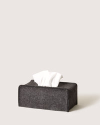 The graf lantz dark gray, rectangular tissue box with a fabric texture captures a minimalist silhouette. White tissues are partially pulled out, and it sits elegantly against a plain, light background, exuding an understated charm.