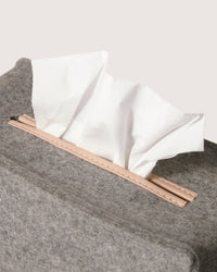 A close-up of a sustainable graf lantz gray felt tissue box, crafted from Merino Wool, with white tissues peeking out against a light background.