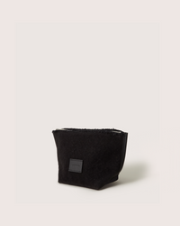 The Graf Lantz artisanal black Hana pouch, designed as a rectangular toiletry bag, features a small label on the front. It stands upright against a white background, showcasing its understated elegance.