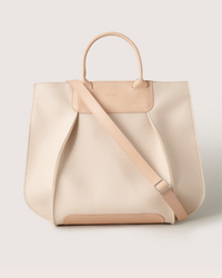 The Graf Lantz Frankie Tote features a structured silhouette in beige with two handles and a detachable shoulder strap, complemented by its rectangular shape with a slightly curved top for both style and functionality.