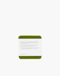 A graf lantz green square coaster with rounded edges lies against a white background, resembling Beer Felt. It features text about ceramic coaster history, though its illegible. A website URL is visible at the bottom.