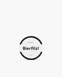 A Bierfilzl Merino Wool Round Coaster from a 4-pack, crafted from German Merino wool, is black with a label reading Bierfilzl, graf lantz, and MADE IN USA displayed on a plain white background.
