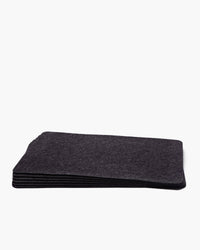 A stack of graf lantz designer-inspired dark gray rectangular felt pads, crafted from sustainable merino wool, sits elegantly on a white background.