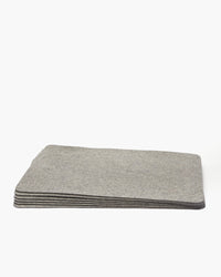 A stack of graf lantz gray rectangular felt mats is neatly arranged against a white background. Resembling Merino wool placemats, their smooth edges and uniform thickness create a designer-inspired, clean, minimalist appearance.