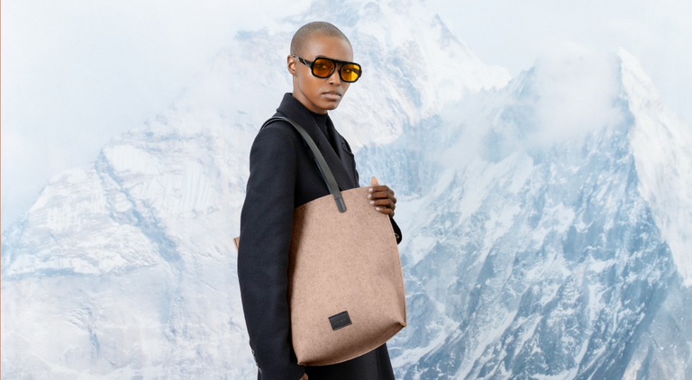 A person in a light dress holds a large handbag against a green leafy background. Text reads: 30% Off Bags - Spring Clean Sale. *Excludes everyday icons and final sale.