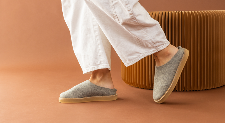 Merino Wool coasters in different shapes and colors by Graf Lantz and  leather coaster holders on a wooden tabletop 