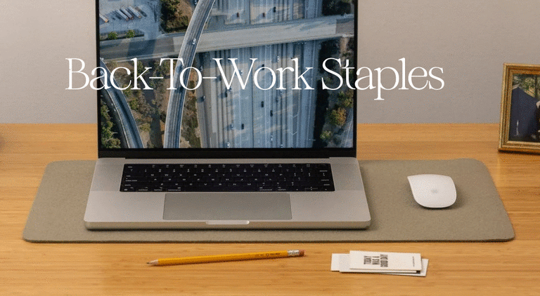A tidy desk setup with a laptop, notebook, and organizer; a tissue box and books on a shelf; and a person holding a navy tote bag. Text reads: 25% off Back-To-Work Staples. Shop Now.
