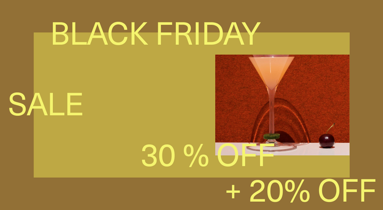 A hand holding a glass of pink champagne with a red felt U charm on the stem. Almonds and a candle are in the background, set on a dark gray surface.