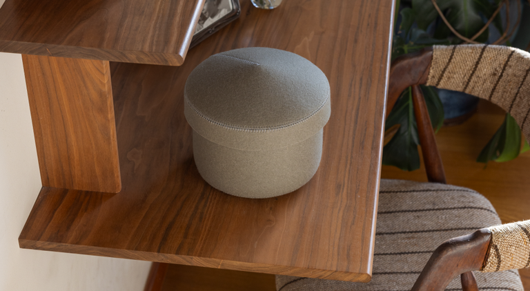 Two gray felt storage containers on a bathroom counter. One is open, holding a pouch and a small bottle. The other is closed, placed beside a bathtub. Soft textures create a cozy, minimalist feel.