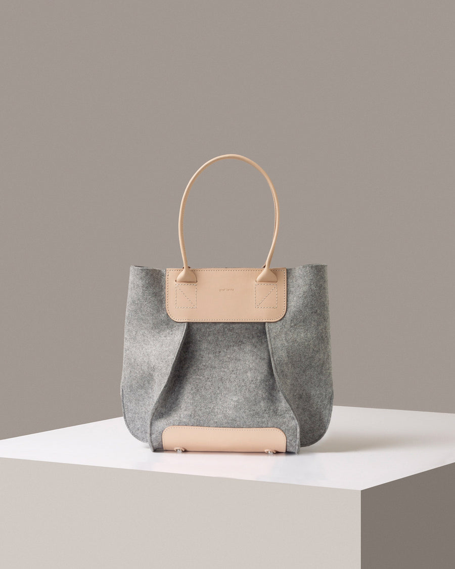 A Frankie Merino Wool Felt Midi mid-sized tote bag in light grey standing on a white base, front view