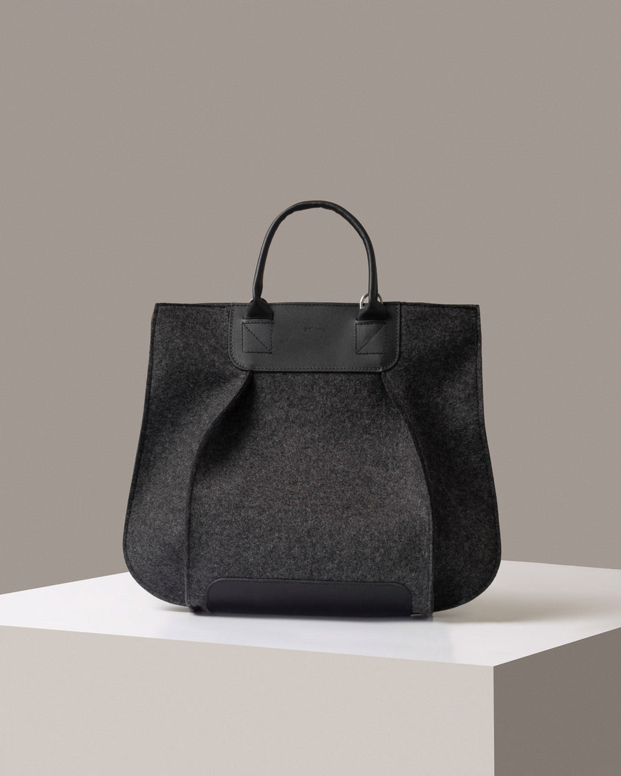 A timeless tote bag, Franke-collection by Graf Lantz, from Merino Wool Felt in dark gray standing on a white base, front view