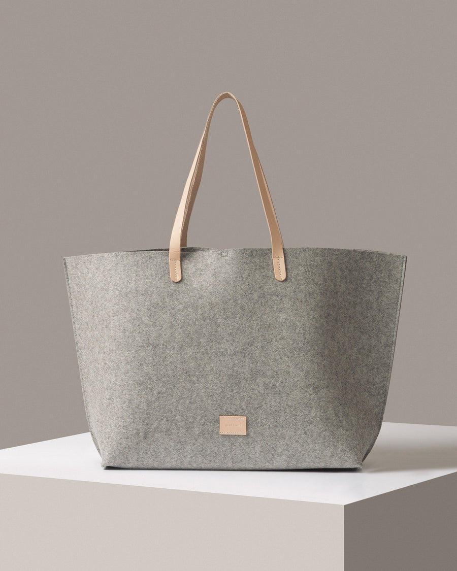 A Hana Merino Wool Felt Boat Bag in grey standing on a white base, front view