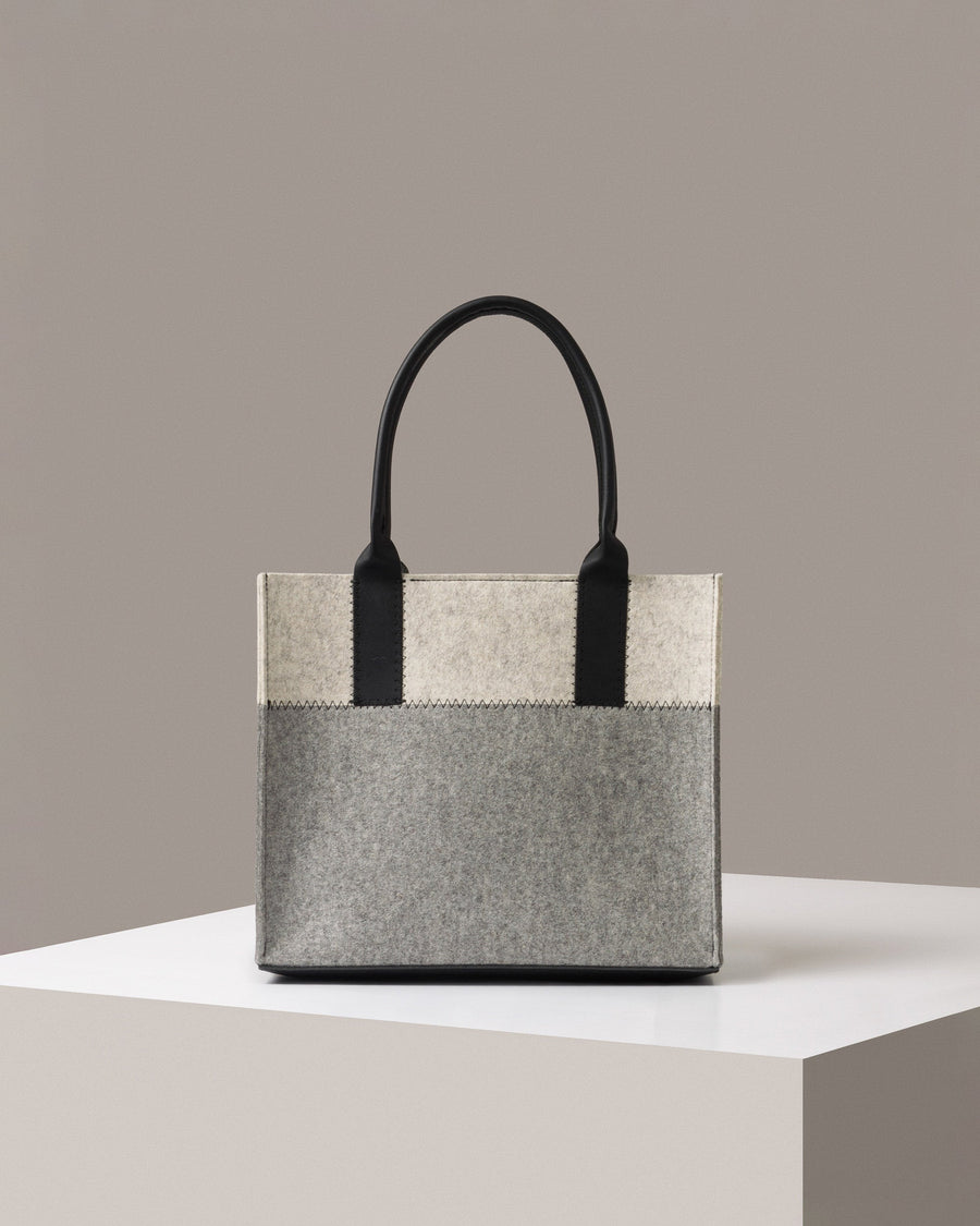 A mid-sized Merino Wool Felt Tote bag standing on a white base, front view