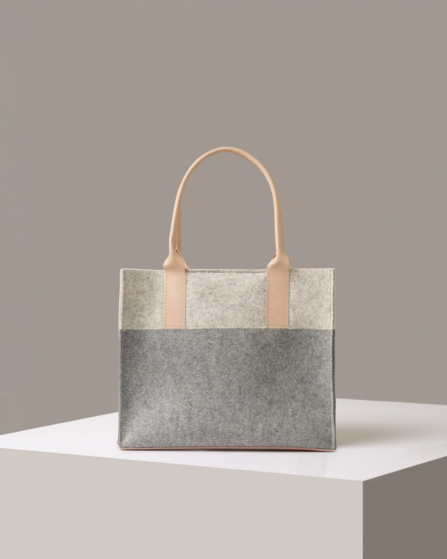 A mid-sized Merino Wool Felt Tote bag standing on a white base, front view