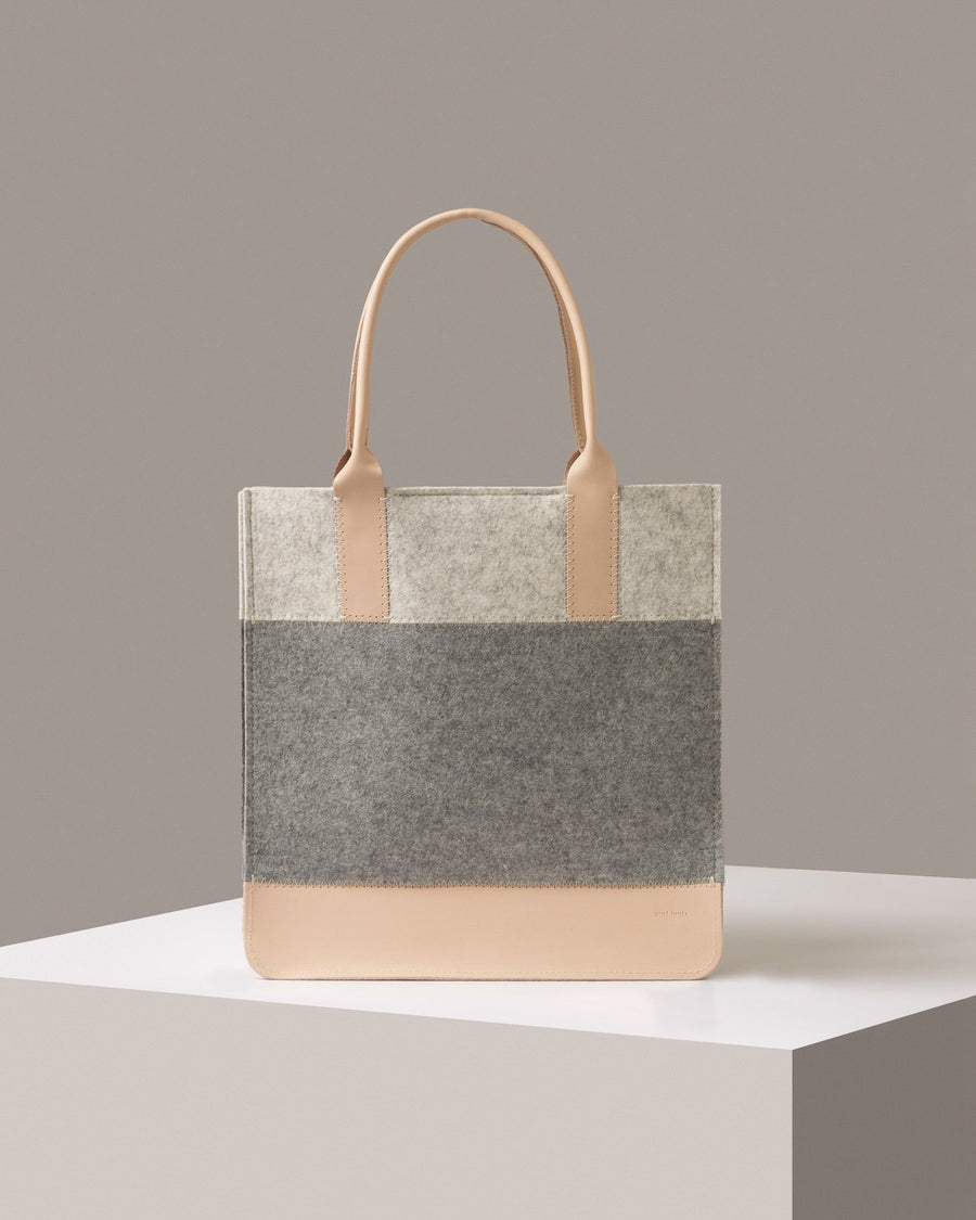 A Jaunt Merino Wool Felt Tote by Graf Lantz in white, gray, and beige colors standing on a white base, front view